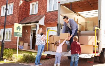 Family Unpacking Moving In Boxes From Removal Truck